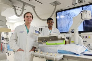 Drs. Rajesh Sachdeva and Michael McDaniel use joysticks to direct the robot to make millimeter-sized movements that are more precise for stent placement and measurement.